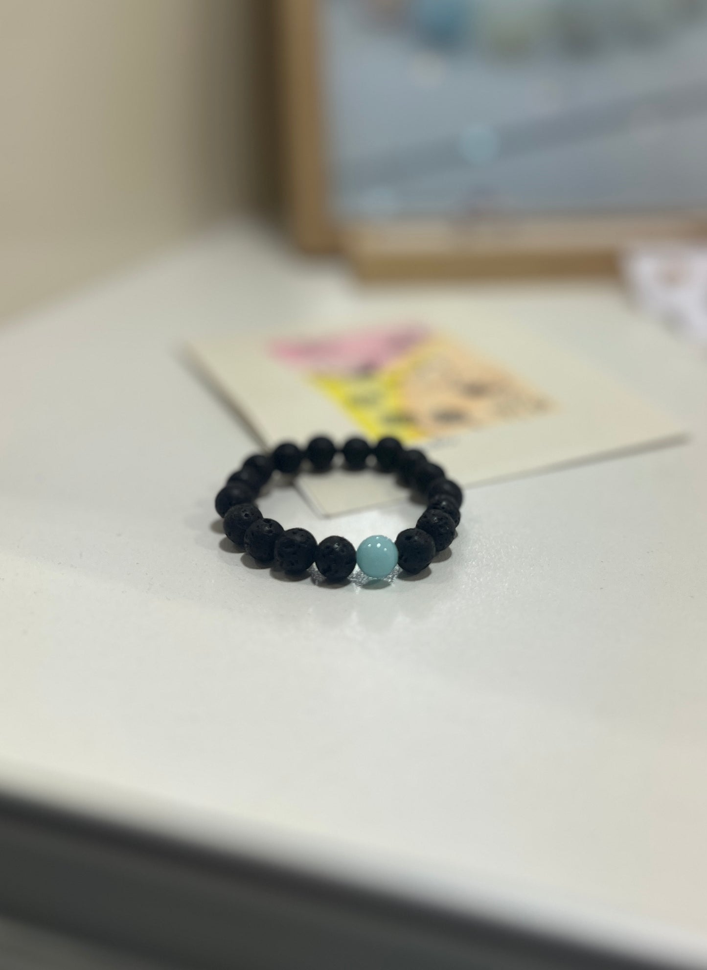 Black beaded bracelet with a blue bead on a light surface