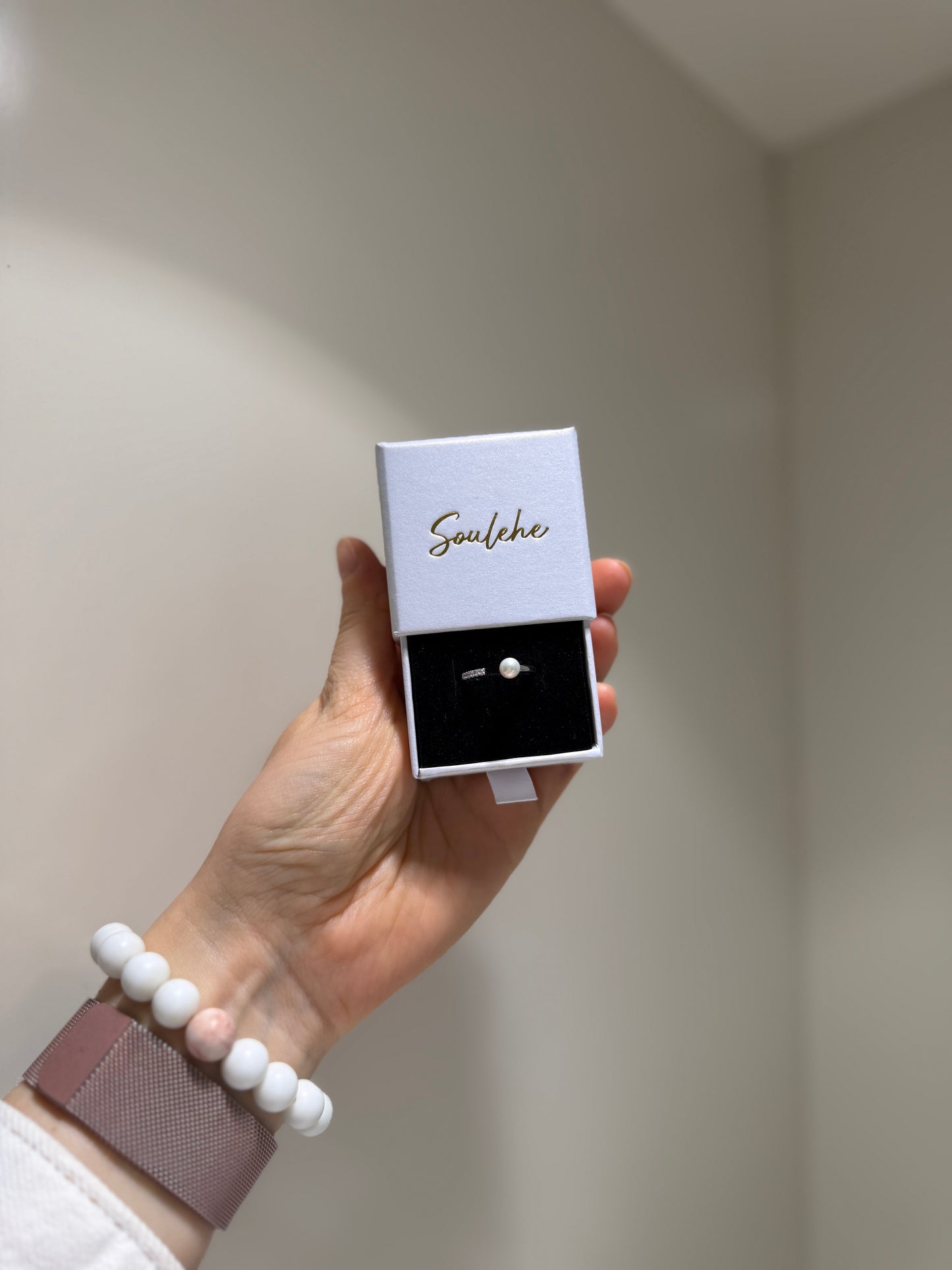 Hand holding a jewelry box with 'Soulehe' branding against a neutral background