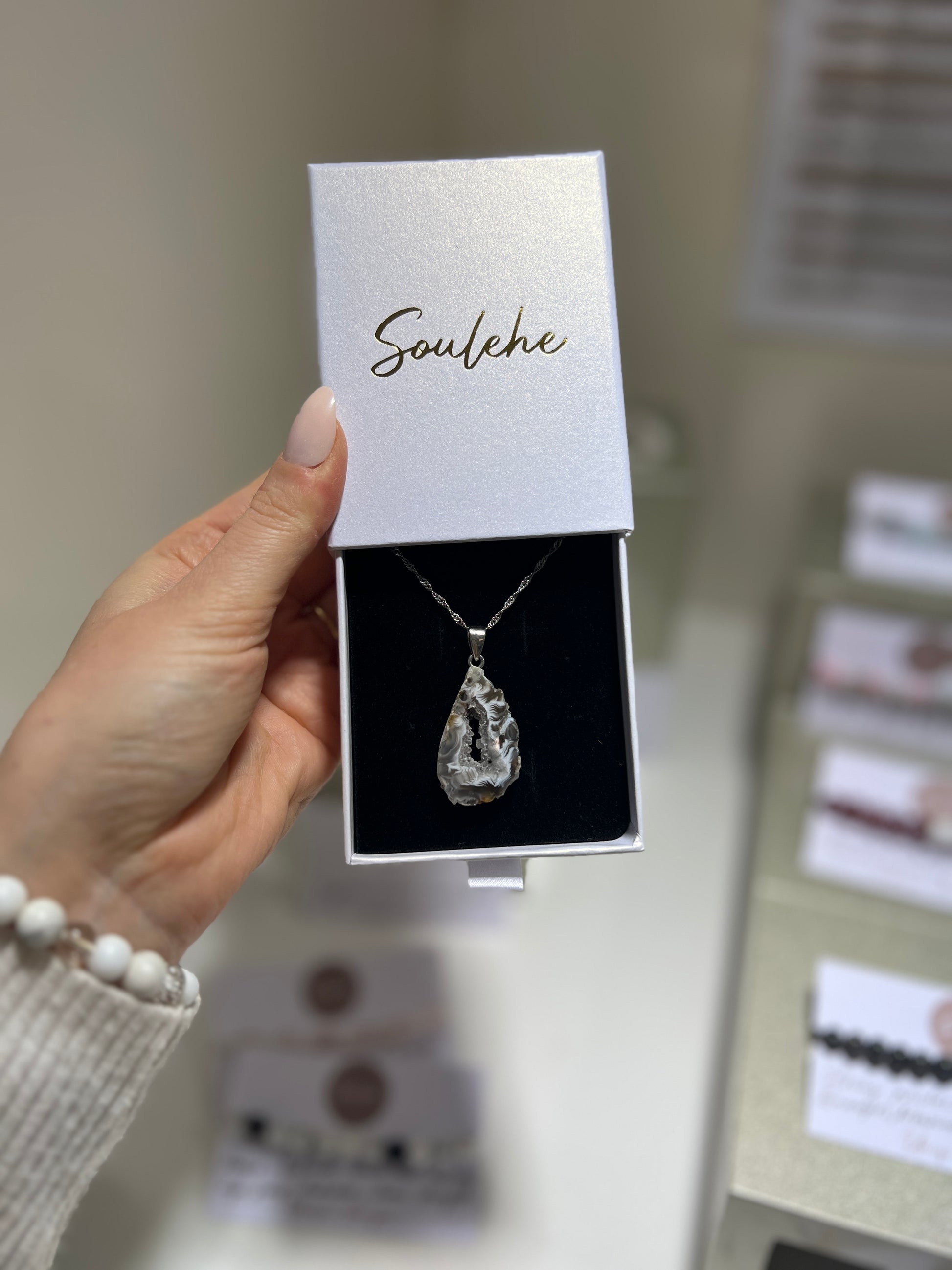 Necklace in a 'Soulehe' box held by a hand with blurred background