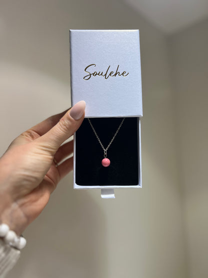 Necklace with a pink pendant in a 'Soulehe' box held by a hand.