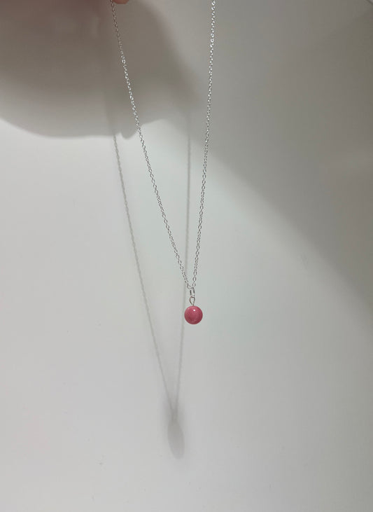 Necklace with a pink bead on a white background