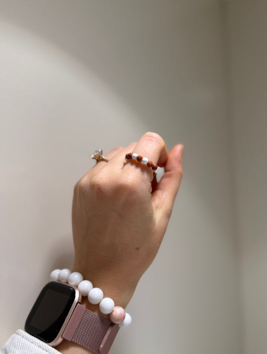 Hand wearing a smartwatch and bracelet on a neutral background