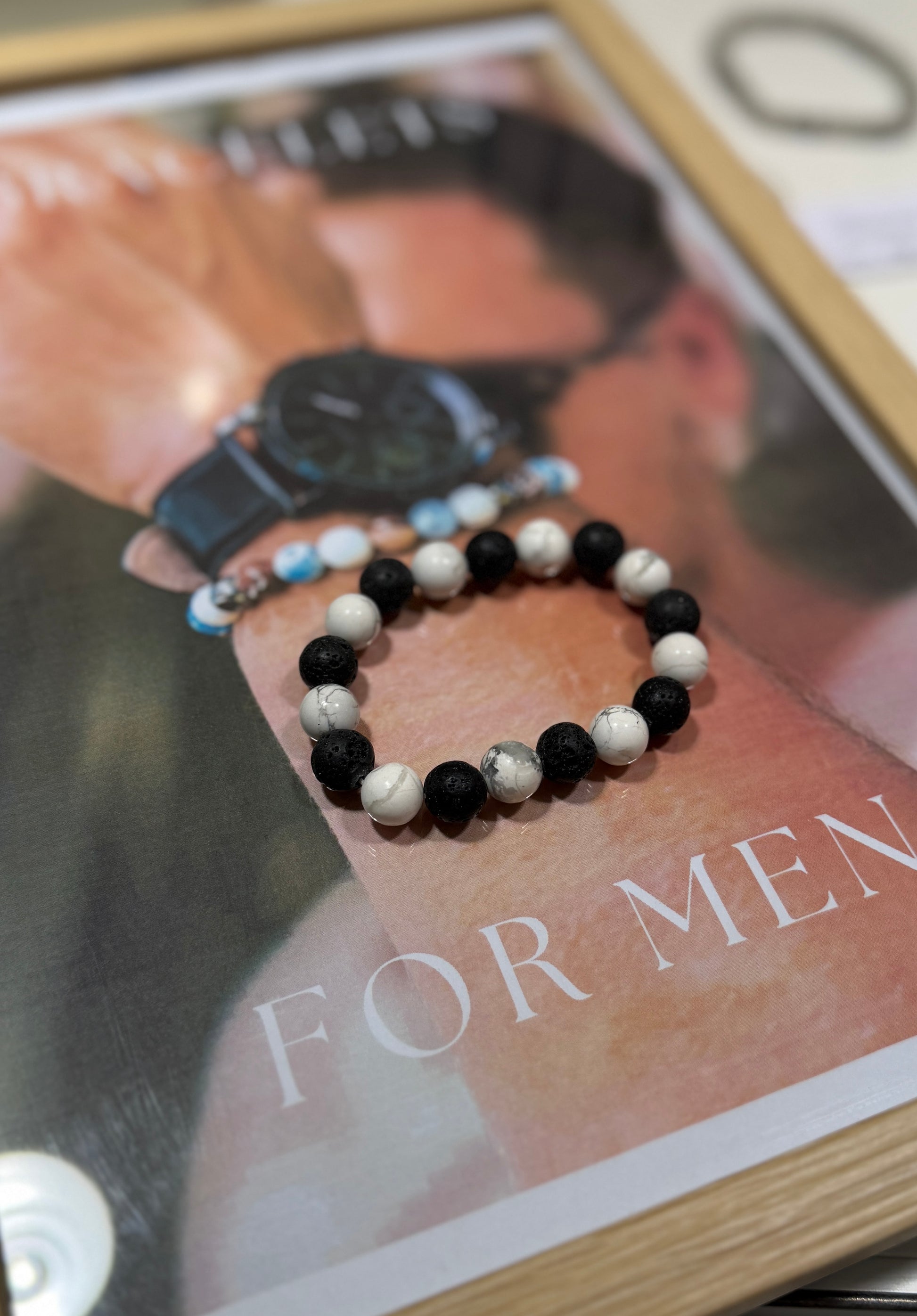 Black and white beaded bracelets on a magazine with 'For Men' text