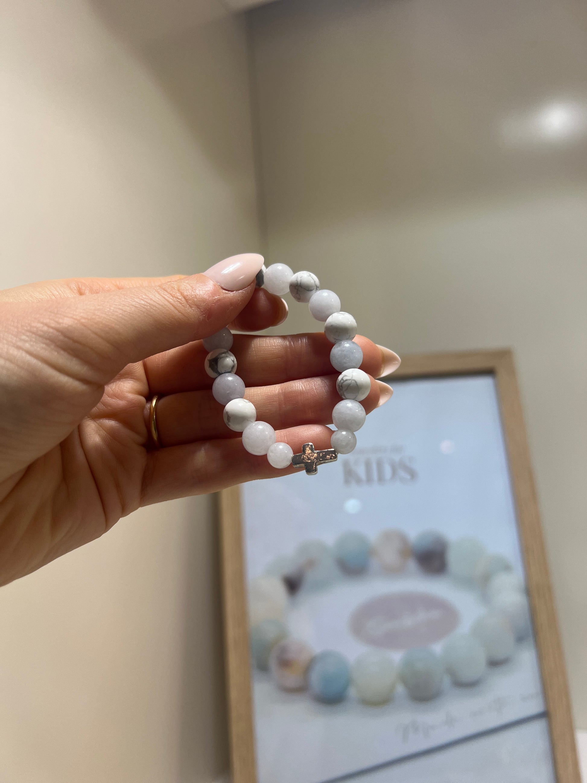 Hand holding a white beaded bracelet with a blurred background