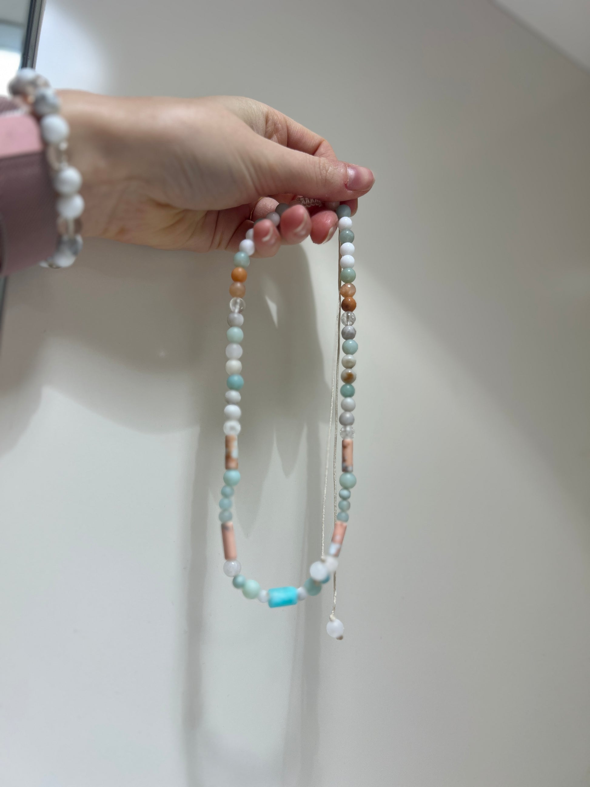 Hand holding a beaded necklace against a plain background