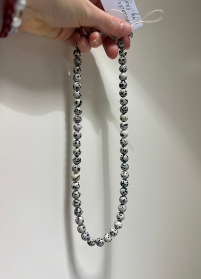 Hand holding a beaded necklace with a plain background