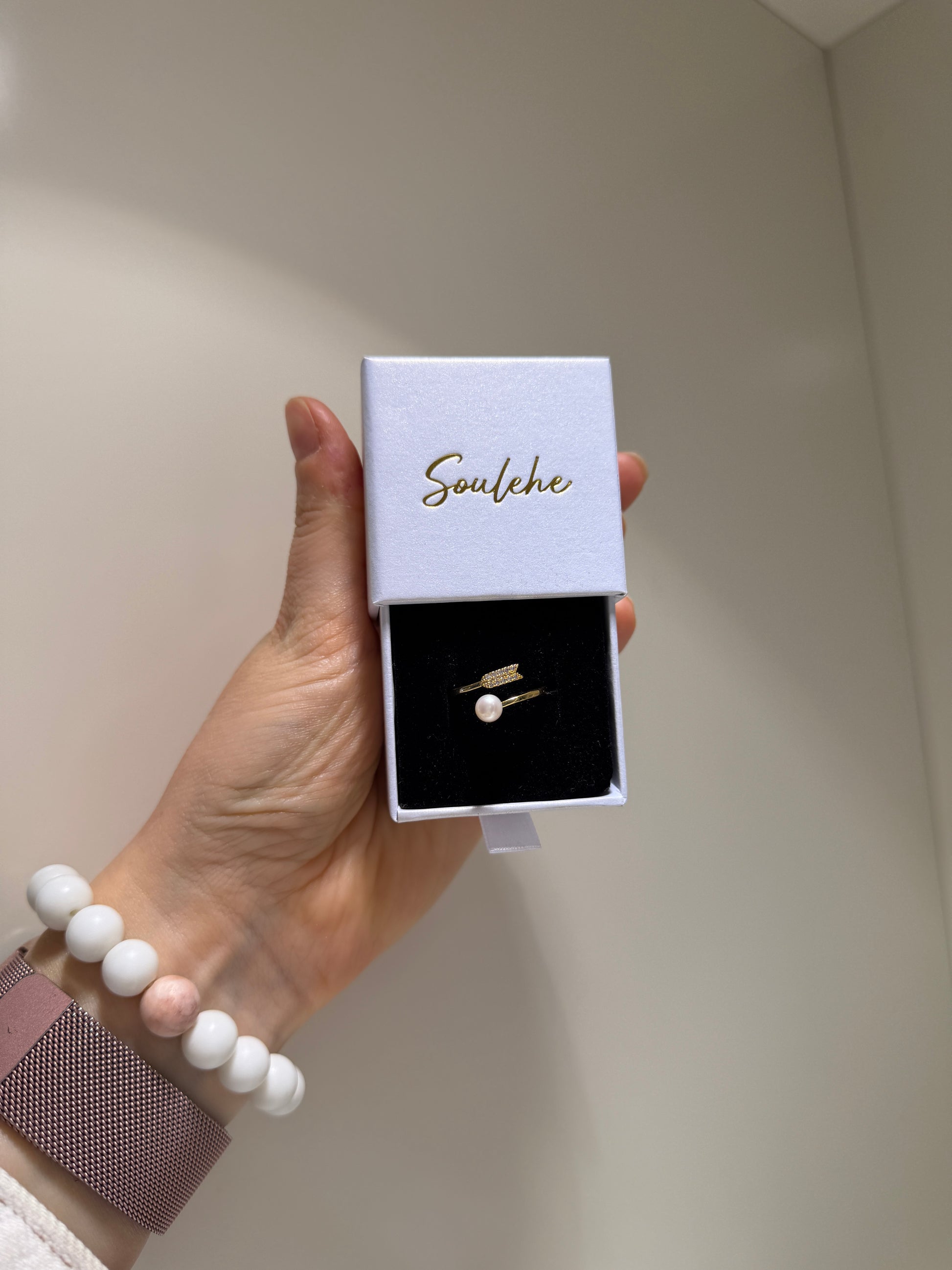 Hand holding a jewelry box with earrings inside, branded 'Soulehe'.