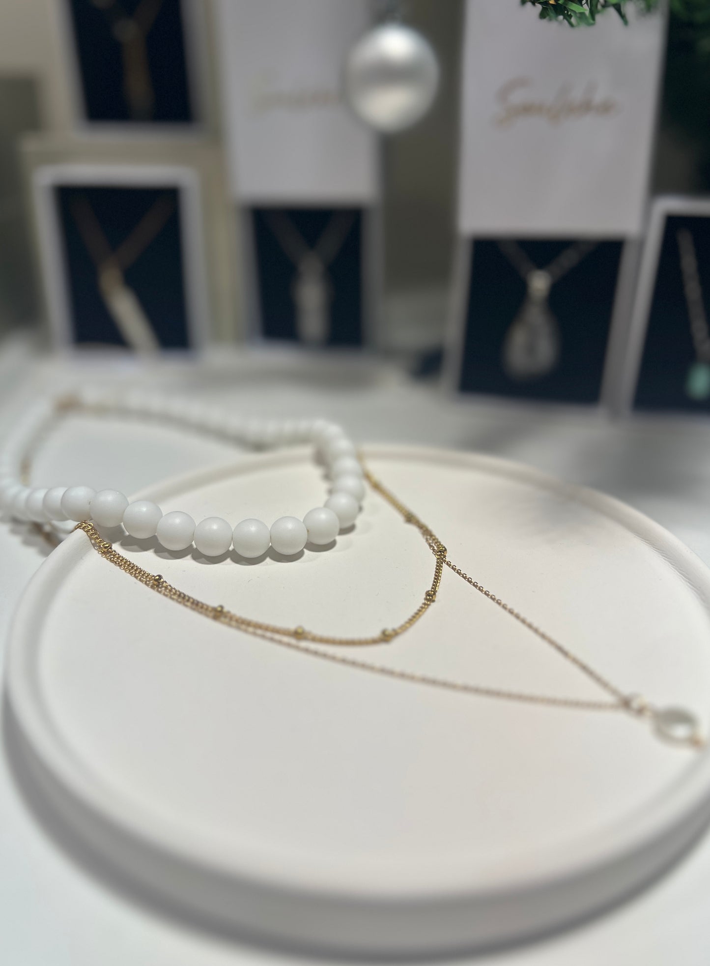 Two necklaces on a white surface with a blurred background