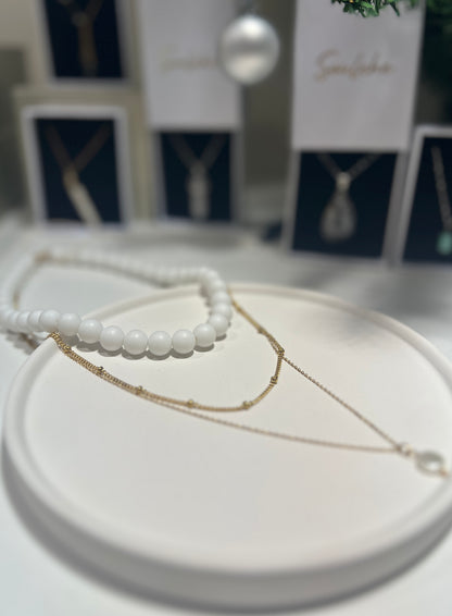 Two necklaces on a white surface with a blurred background