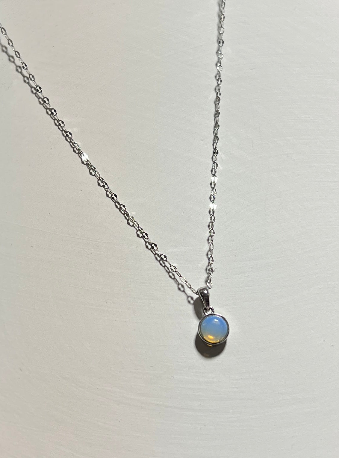 Necklace with a small round gemstone pendant on a light gray background