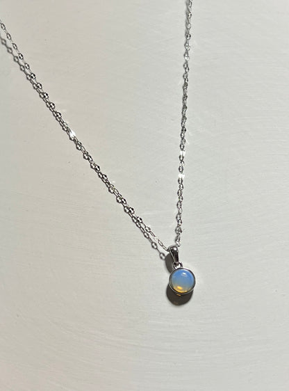 Necklace with a small round gemstone pendant on a light gray background