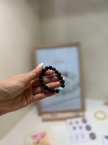 Hand holding a black beaded bracelet with a blurred background