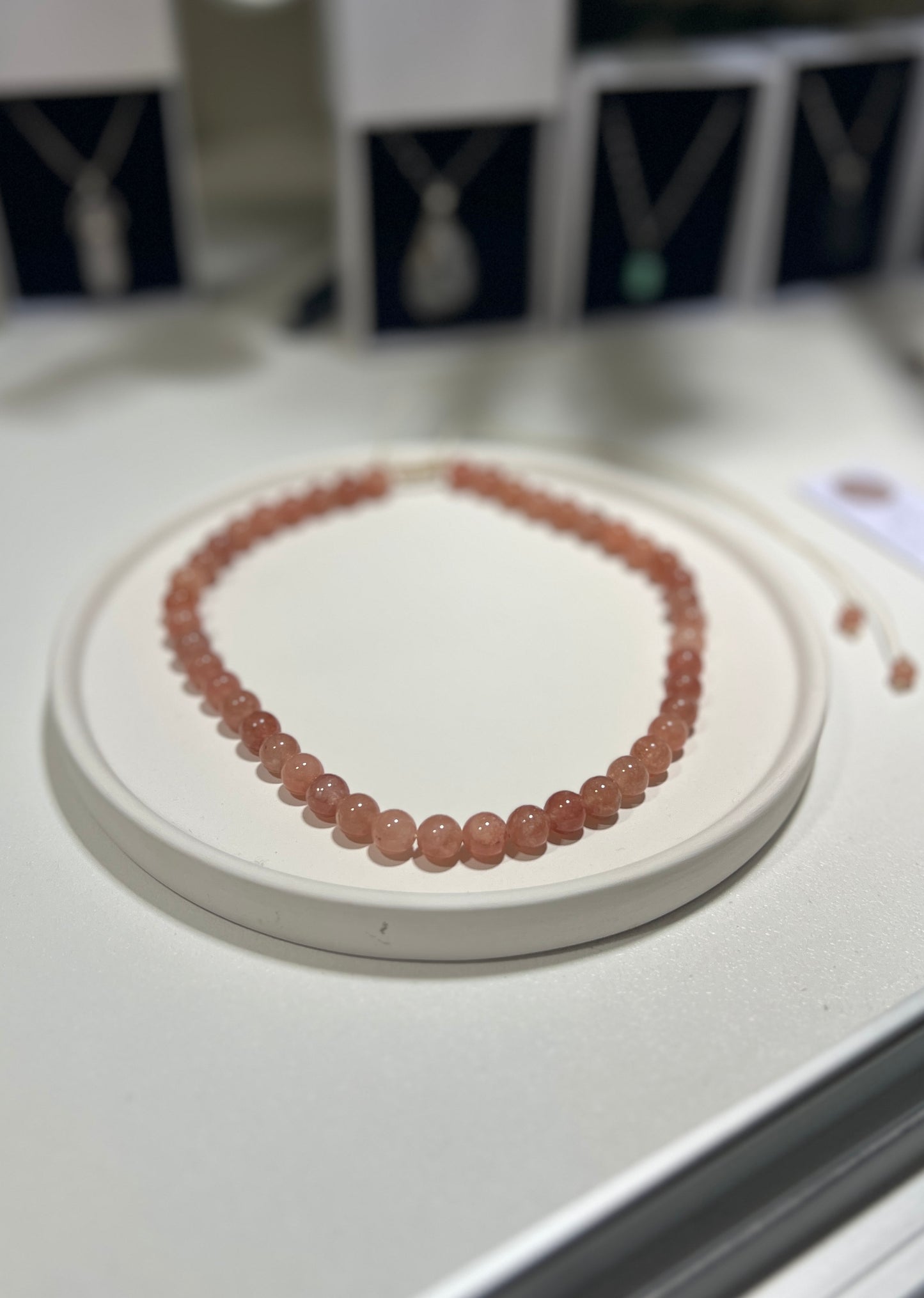 Necklace with pink beads on a white stand with a blurred background