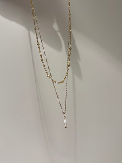 Two gold necklaces on a white background